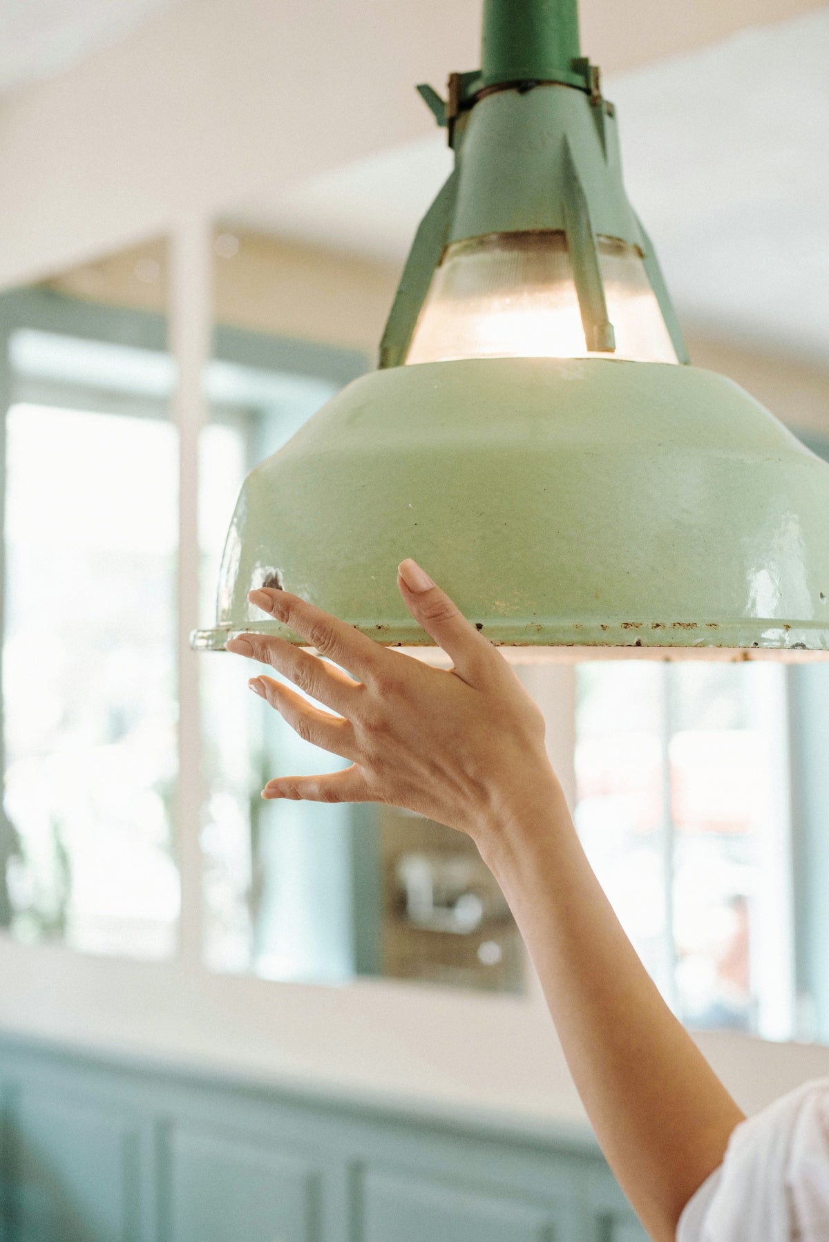 A hand gently touches a green light fixture